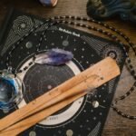 Astrology-themed flat lay featuring a birthdate book, crystals, and necklace on a wooden surface.
